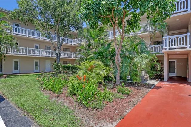 a view of a swimming pool with a garden and palm trees