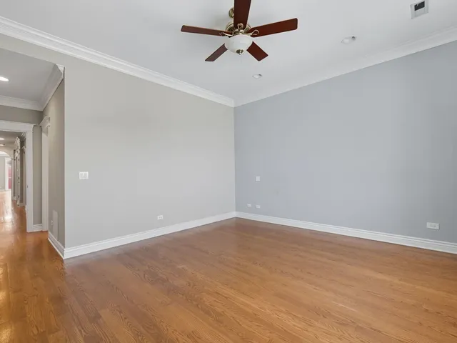 an empty room with a ceiling fan and wooden floor