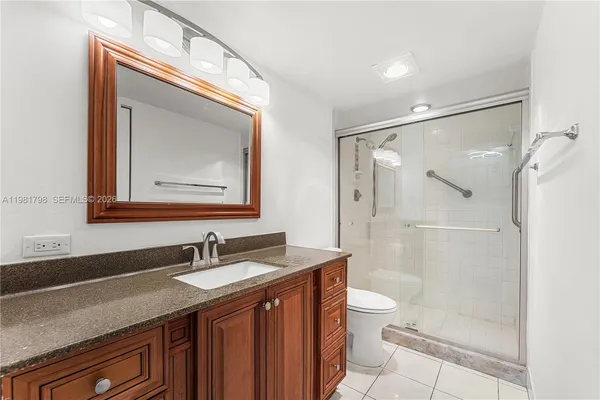a bathroom with a granite countertop sink mirror toilet and shower