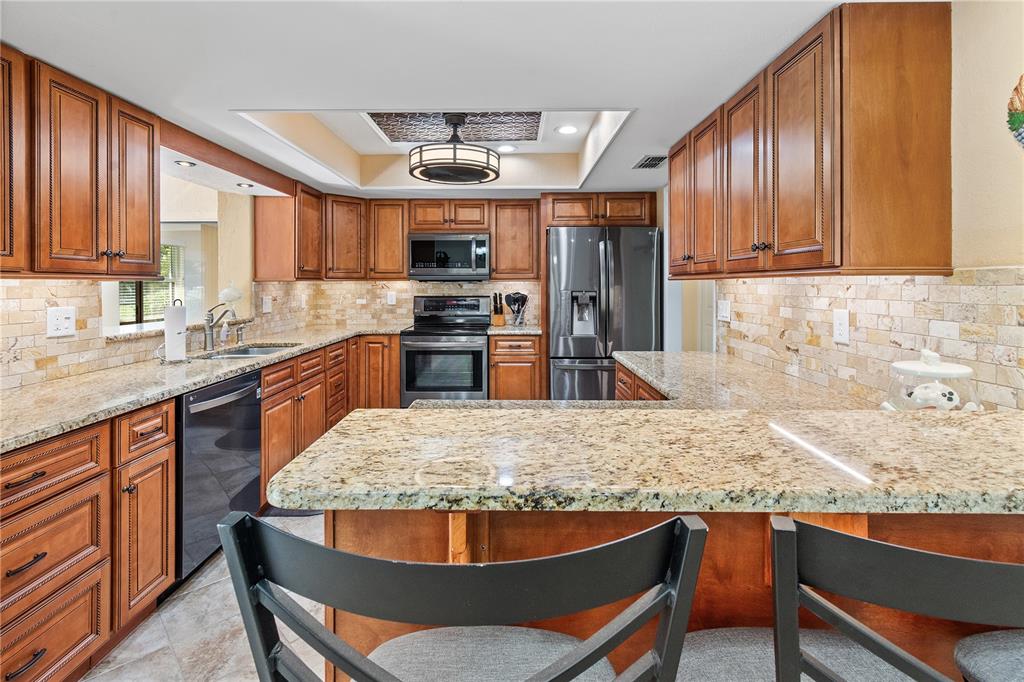 731 Canberra Road Winter Haven, FL 33884 - Photo 2 of 51 a kitchen with stainless steel appliances granite countertop a stove top oven a sink dishwasher and wooden cabinets with wooden floor