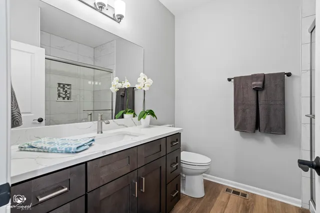 a bathroom with a granite countertop toilet sink and mirror