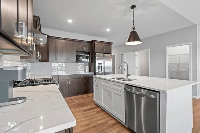 a kitchen with stainless steel appliances granite countertop a sink a stove and a refrigerator