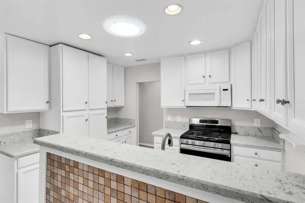 a kitchen with granite countertop white cabinets and stainless steel appliances