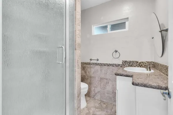 a bathroom with a granite countertop sink and a toilet