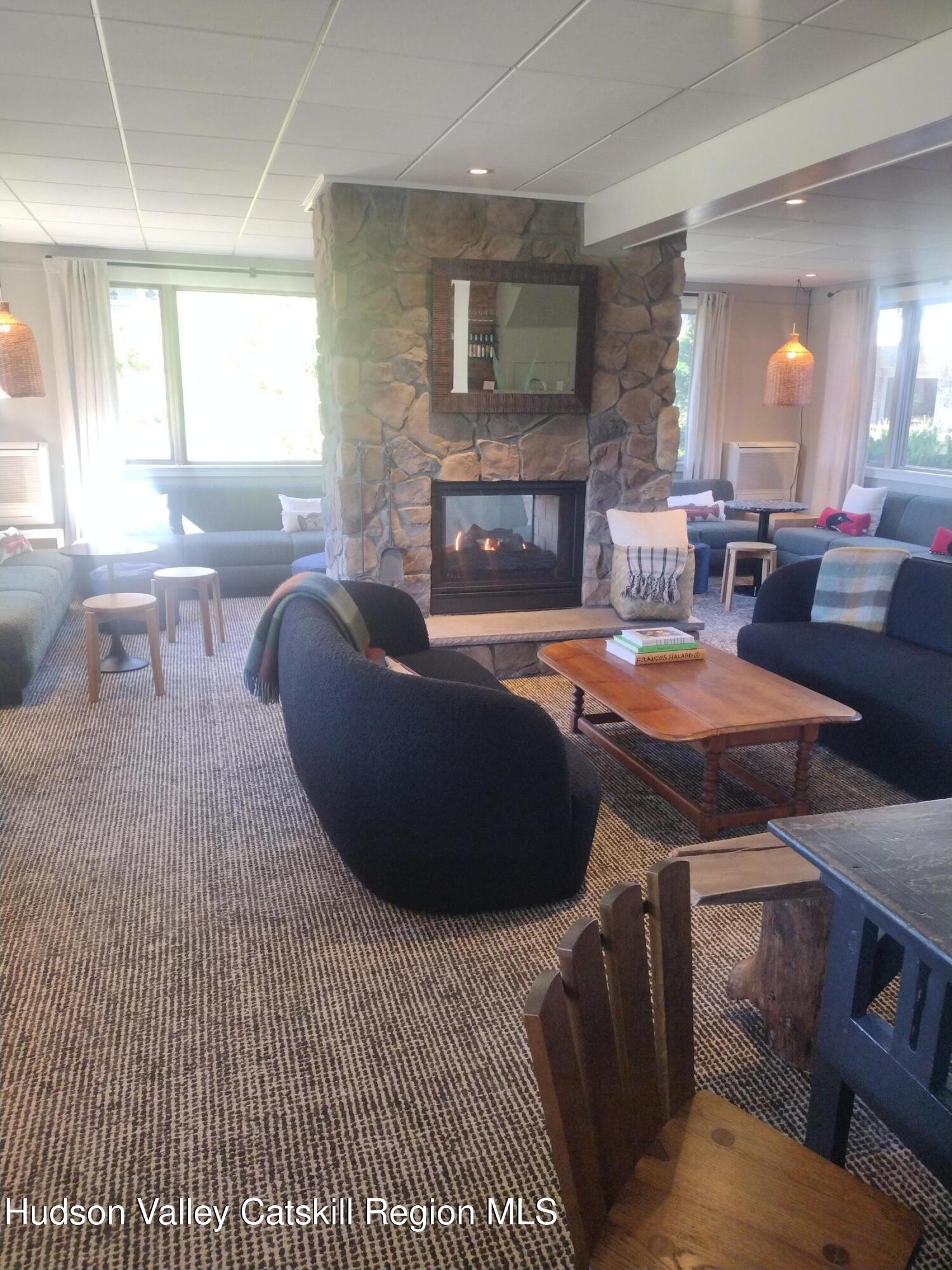 5220 Highway 23, Unit 126 Windham, NY 12496 - Photo 10 of 27 a living room with furniture a fireplace and a large window