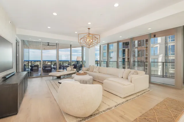 a living room with furniture a large window and a chandelier