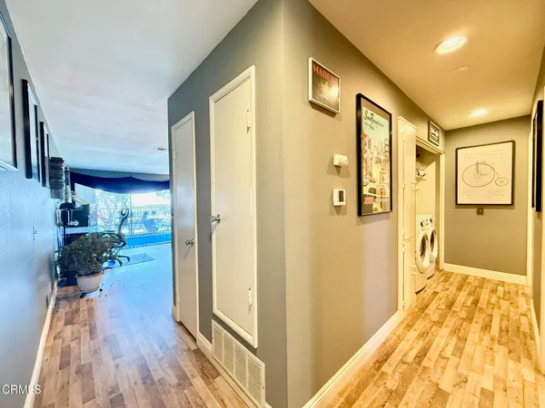a view of a hallway with wooden floor and a bathroom