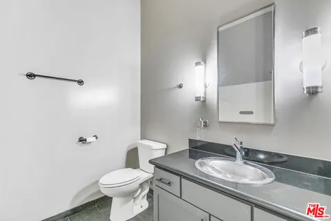 a bathroom with a granite countertop sink toilet and a mirror