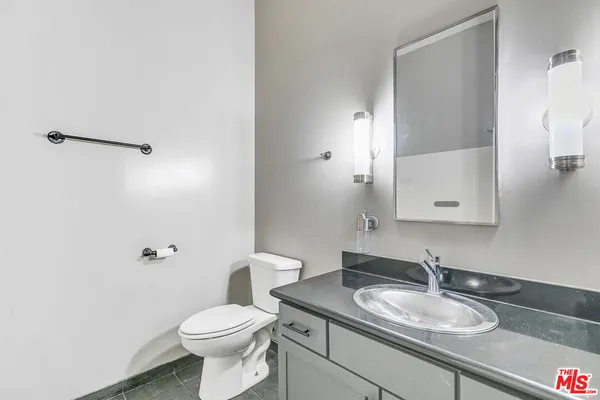 a bathroom with a granite countertop sink toilet and a mirror