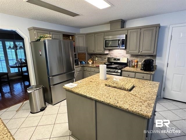 23393 Miflin Road Foley, AL 36535 - Photo 4 of 12 Kitchen with light tile patterned floors, a kitchen island, gray cabinetry, stainless steel appliances, and tasteful backsplash