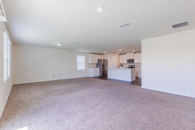 a view of a big room with windows and chandelier fan