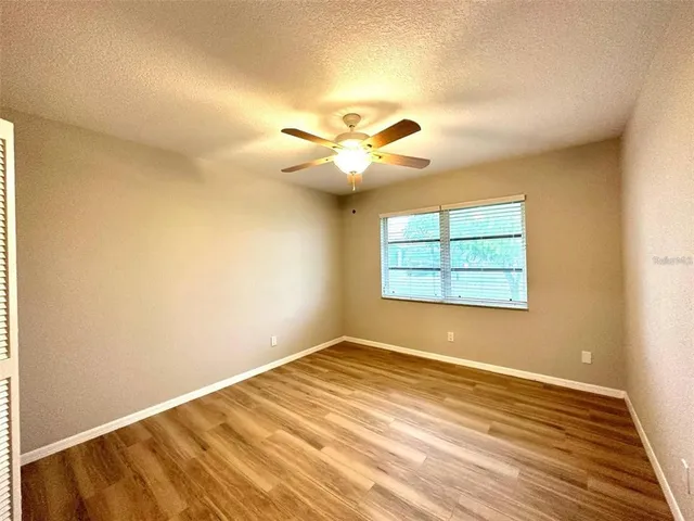 a view of a room with wooden floor and a ceiling fan