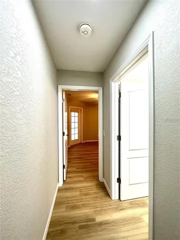 a view of a hallway with wooden floor and a bathroom