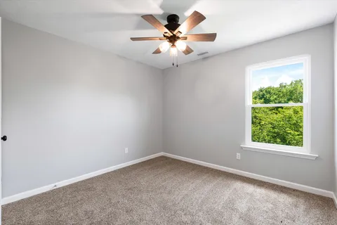 an empty room with a window and a fan