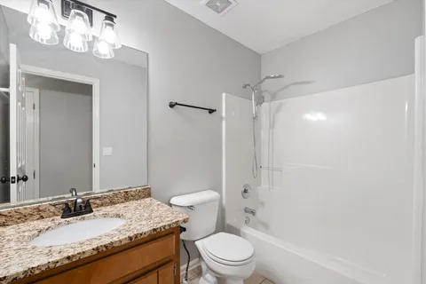 a bathroom with a granite countertop sink a toilet and shower