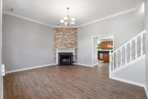 a view of an empty room with wooden floor fireplace and a window