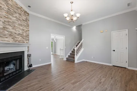a view of an empty room with wooden floor fireplace and a window