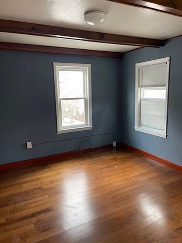 23 Plumer Street Everett, MA 02149 - Photo 6 of 29 an empty room with wooden floor and windows