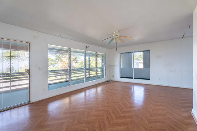 a view of an empty room with a window and wooden floor
