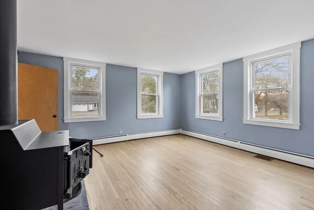 a view of an empty room with glass door and wooden floor