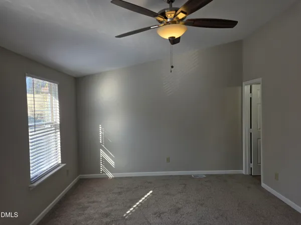 an empty room with windows and fan