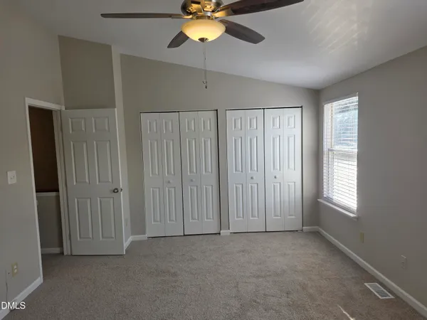 an empty room with windows and fan
