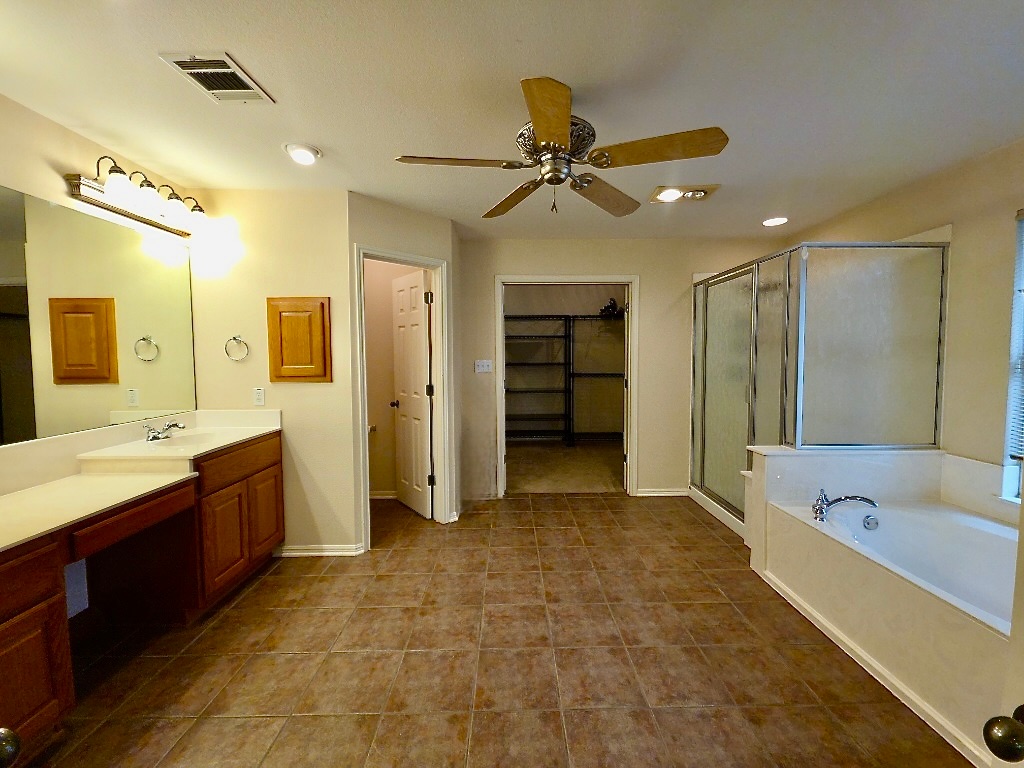 1103 Seton Hall Lane Pflugerville, TX 78660 - Photo 23 of 32 Bathroom featuring a garden tub, a walk in closet, vanity, a stall shower, and recessed lighting
