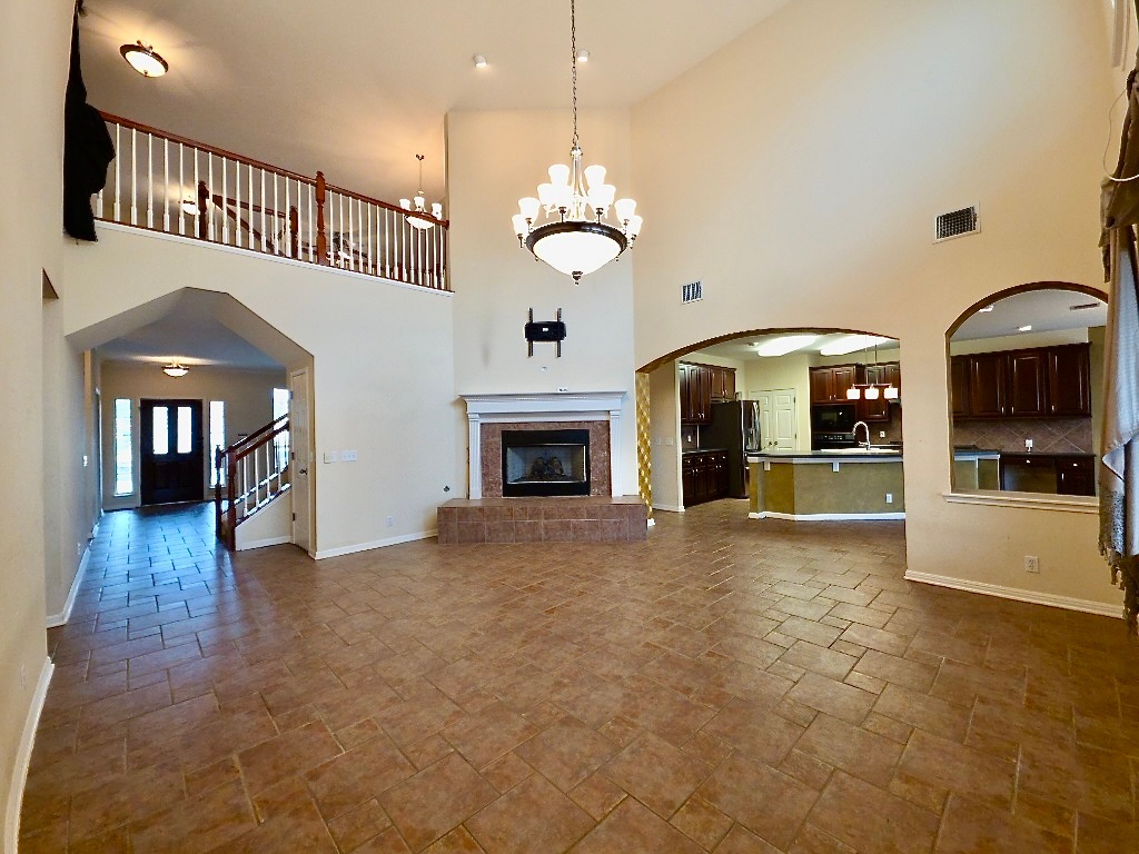 1103 Seton Hall Lane Pflugerville, TX 78660 - Photo 3 of 32 Living room with arched walkways, a glass covered fireplace, tile floors, a towering ceiling and open to the kitchen, breakfast nook and second floor living.