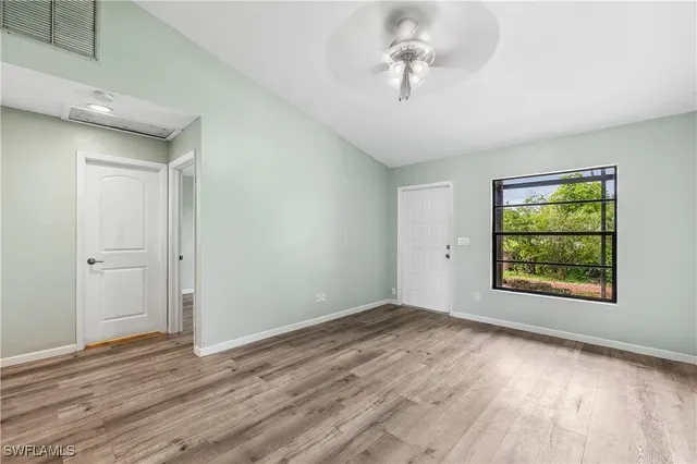 a view of an empty room with a window and wooden floor