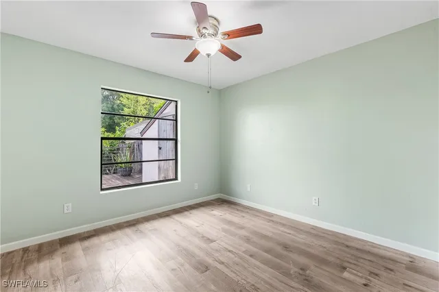 an empty room with windows and ceiling fan