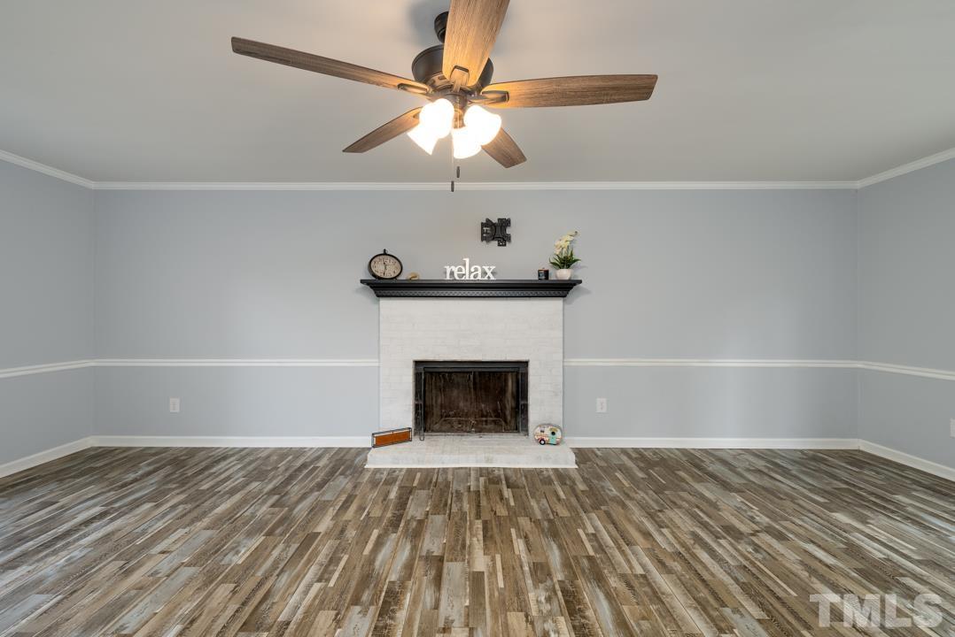 507 Valley Drive Durham, NC 27704 - Photo 2 of 29 a room with a fireplace a ceiling fan and wooden floor
