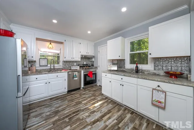 a kitchen with granite countertop a sink window stainless steel appliances and cabinets