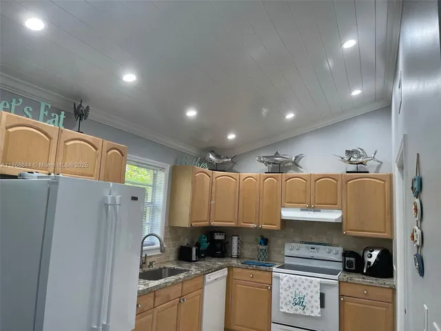 a kitchen with granite countertop a refrigerator a stove a sink a counter space and cabinets