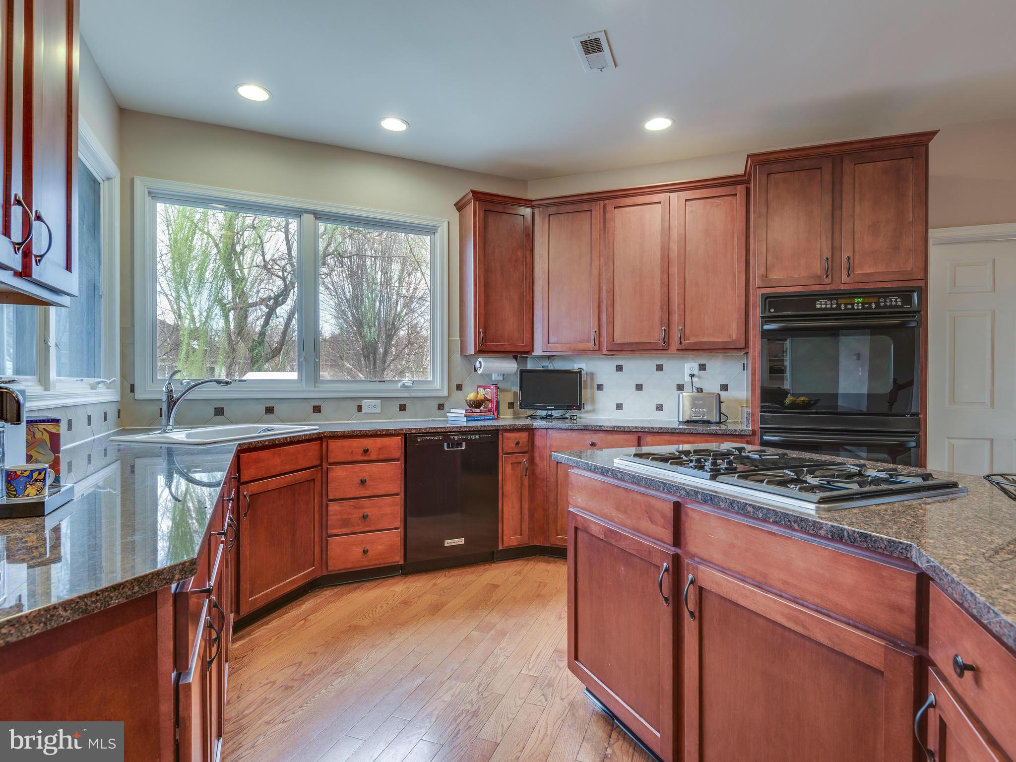 10889 Hunter Gate Way Reston, VA 20194 - Photo 4 of 30 a kitchen with stainless steel appliances granite countertop wooden cabinets a stove a sink and a window