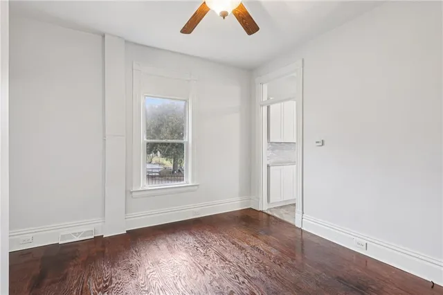 an empty room with wooden floor closet and windows