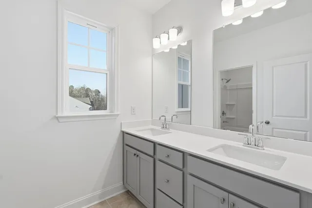 a bathroom with a sink double vanity granite tub shower and a mirror