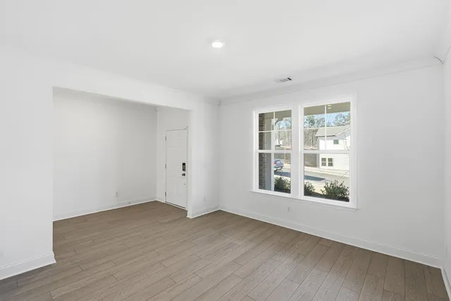an empty room with wooden floor and windows