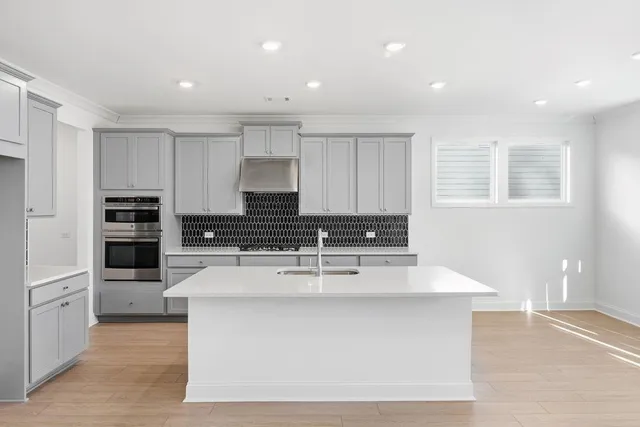 a large kitchen with stainless steel appliances a large counter top a stove and a refrigerator