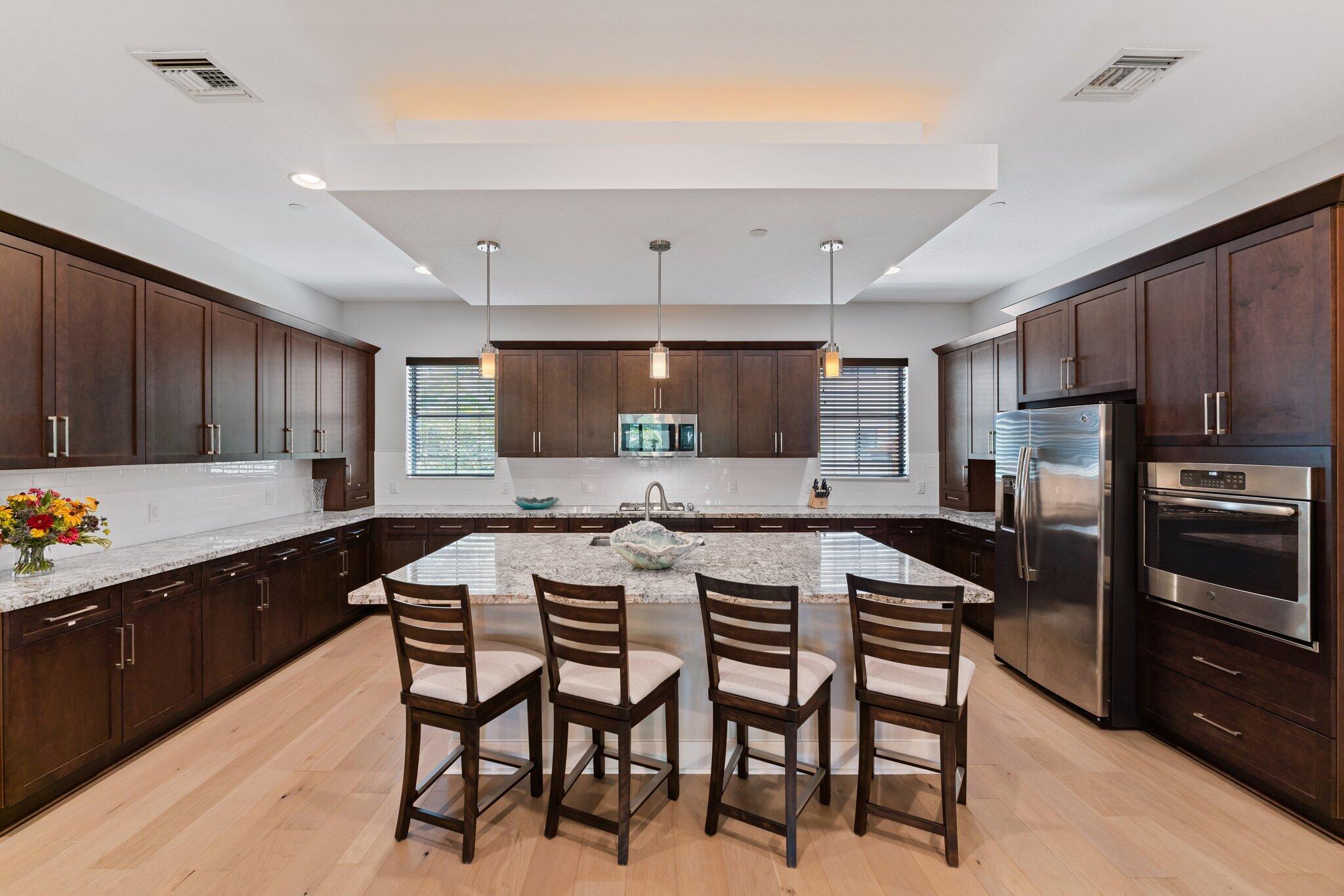 13364 Alton Road Palm Beach Gardens, FL 33418 - Photo 14 of 58 a kitchen with stainless steel appliances a sink a stove a refrigerator cabinets and chairs