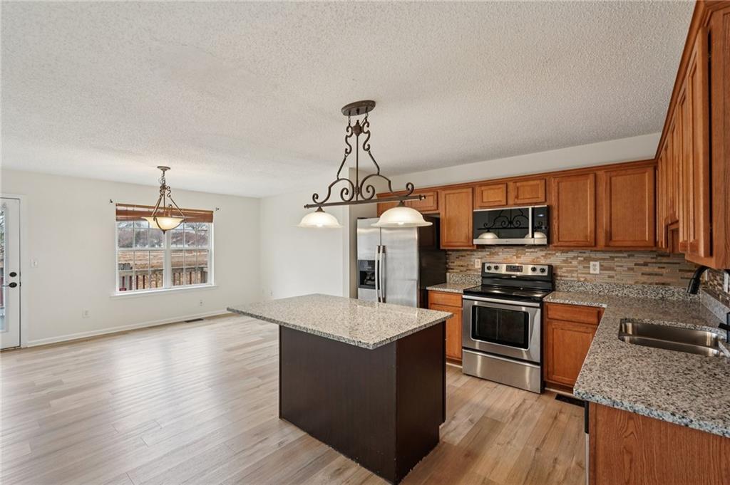 38 Middleton Court Cartersville, GA 30120 - Photo 12 of 46 a kitchen with stainless steel appliances granite countertop a stove top oven a sink dishwasher a refrigerator and a dining table with wooden floor