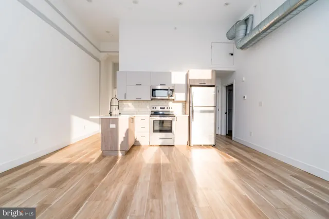 a kitchen with stainless steel appliances a refrigerator and a wooden floor