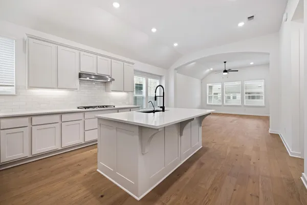 a kitchen with stainless steel appliances granite countertop a stove a sink dishwasher and a refrigerator with wooden floors