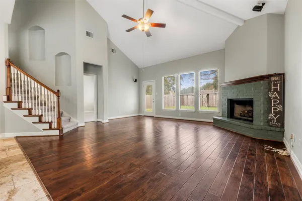 a view of an empty room with wooden floor fireplace and a window