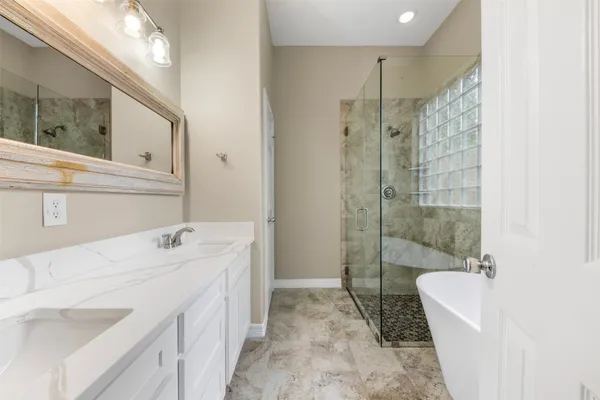 a spacious bathroom with a tub sink mirror and shower