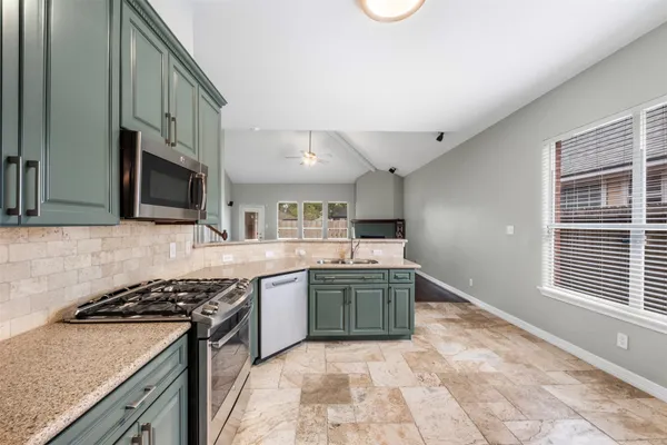 a kitchen with stainless steel appliances granite countertop a stove a sink and a microwave
