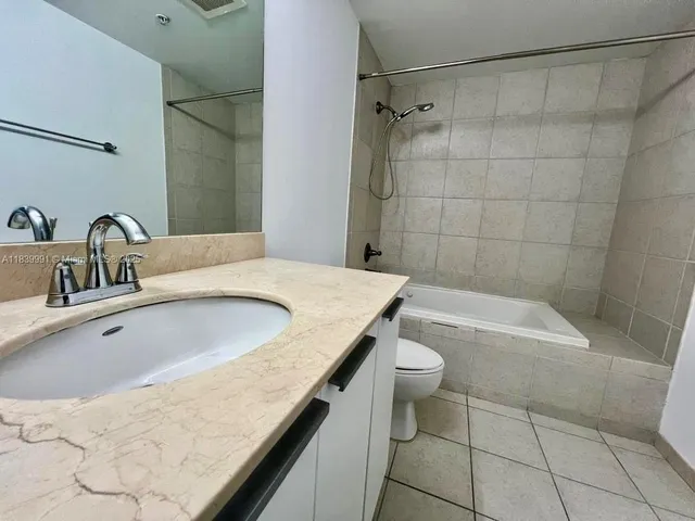 a bathroom with a granite countertop sink a toilet a mirror and shower