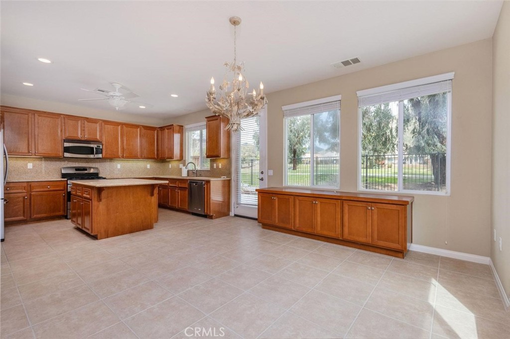 7692 Dutra Drive Hemet, CA 92545 - Photo 19 of 48 a kitchen with stainless steel appliances granite countertop a stove top oven a sink dishwasher a dining table and chairs with wooden floor