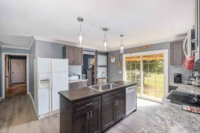 a kitchen with a stove a refrigerator a sink and dishwasher with wooden floor