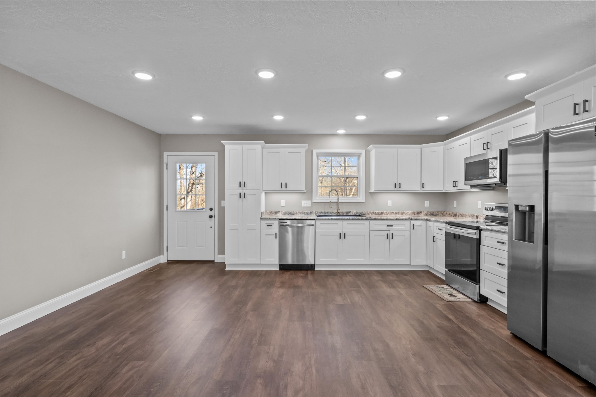 358 Able Street Big Sandy, TN 38221 - Photo 16 of 31 a large kitchen with white cabinets stainless steel appliances and wooden floor