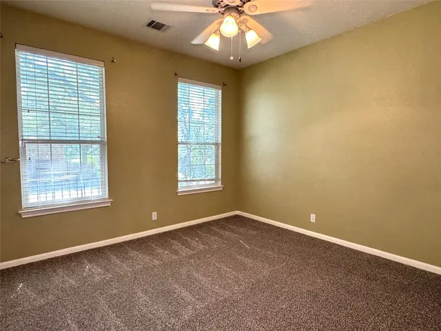 an empty room with windows and chandelier fan